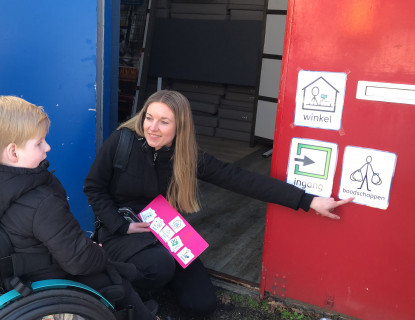 Een behandelaar en een kind in een rolstoel communiceren via ondersteunde communicatie